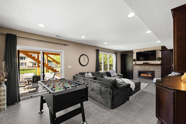 recreation room featuring a glass covered fireplace, recessed lighting, and light tile patterned flooring