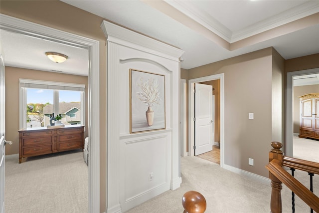corridor featuring light carpet, baseboards, and ornamental molding