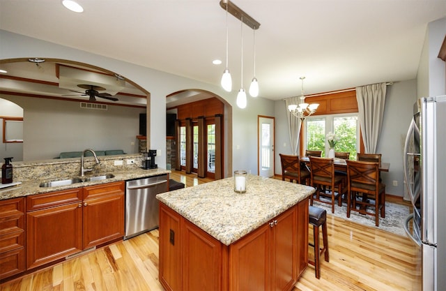 4110 140th St, Urbandale, IA 50323 - kitchen featuring light wood finished floors, ceiling fan with notable chandelier, a sink, arched walkways, and appliances with stainless steel finishes