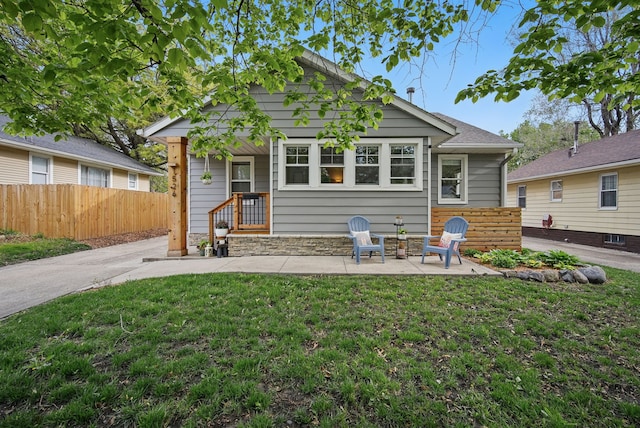 view of front facade with a patio, a front lawn, and fence