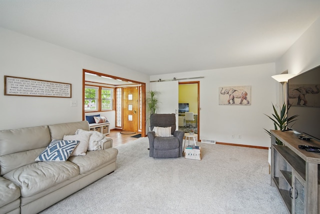 living area with carpet floors, a barn door, and visible vents