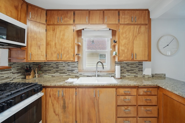 kitchen featuring a sink, range with gas cooktop, light stone countertops, white microwave, and decorative backsplash