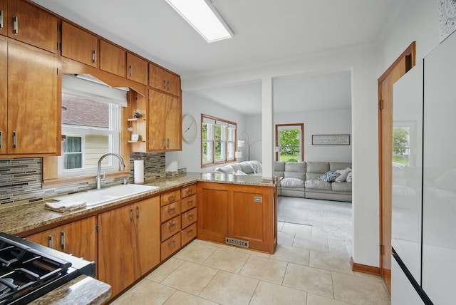 kitchen with a sink, backsplash, visible vents, and brown cabinets