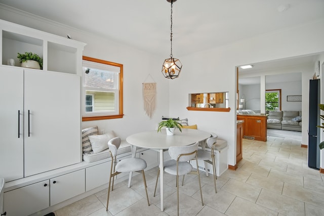 dining room with ornamental molding, a notable chandelier, baseboards, and light tile patterned floors