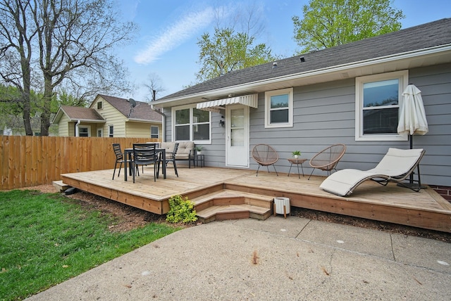 back of property featuring outdoor dining space, fence, a patio, a shingled roof, and a deck