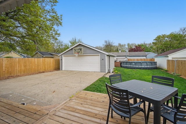 wooden deck featuring a detached garage, an outbuilding, a fenced backyard, a fenced in pool, and a lawn