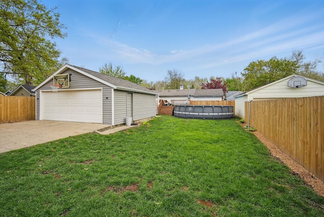 view of yard with a fenced backyard, a detached garage, a fenced in pool, and an outbuilding