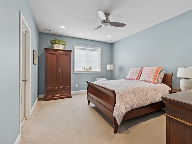 bedroom featuring light colored carpet, a textured ceiling, visible vents, ceiling fan, and baseboards