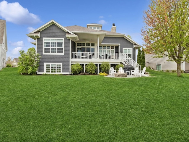 rear view of property with an outdoor fire pit, a yard, a patio area, and a chimney