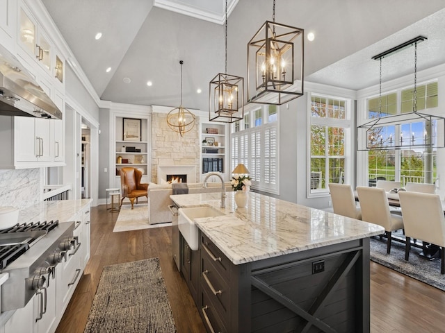 kitchen featuring a notable chandelier, stainless steel gas cooktop, a sink, high vaulted ceiling, and white cabinets