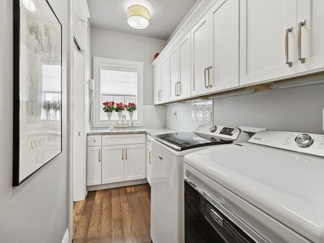 clothes washing area with washing machine and dryer, cabinet space, a sink, and dark wood-type flooring