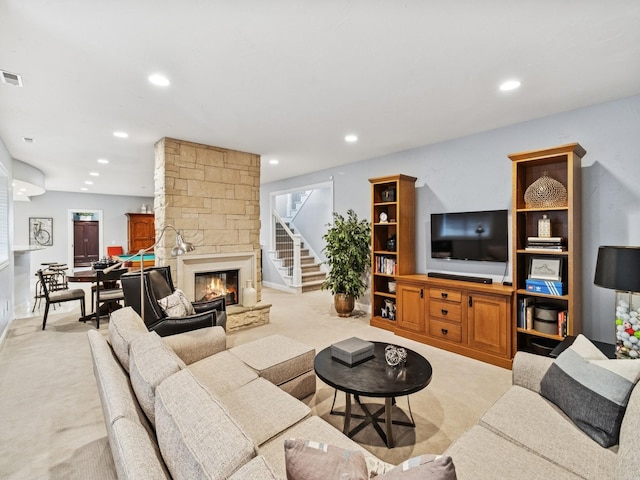 living area featuring a stone fireplace, light carpet, visible vents, and recessed lighting
