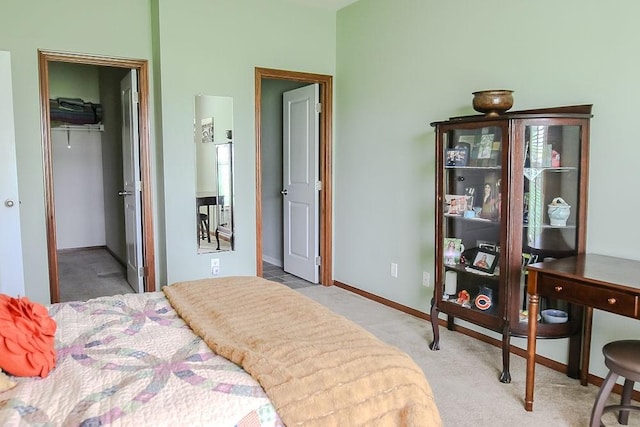 carpeted bedroom with a spacious closet, a closet, and baseboards