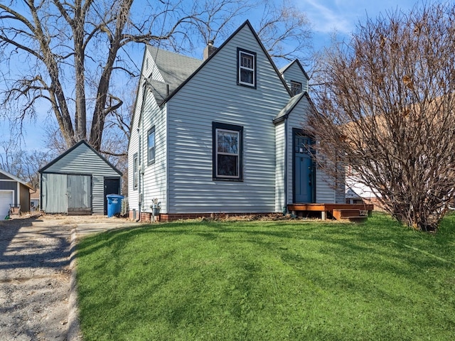 view of front of home featuring a detached garage, an outbuilding, and a front yard