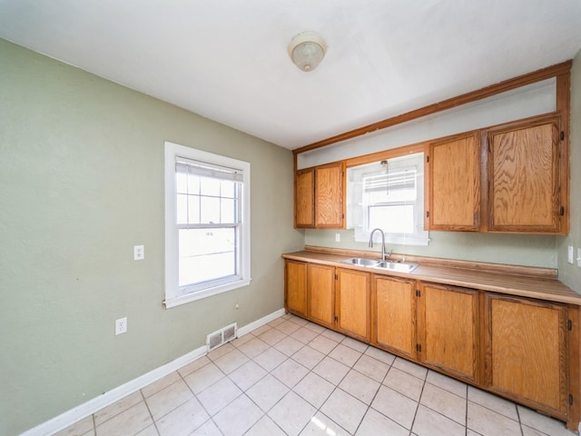 kitchen with brown cabinetry, light countertops, visible vents, and a sink