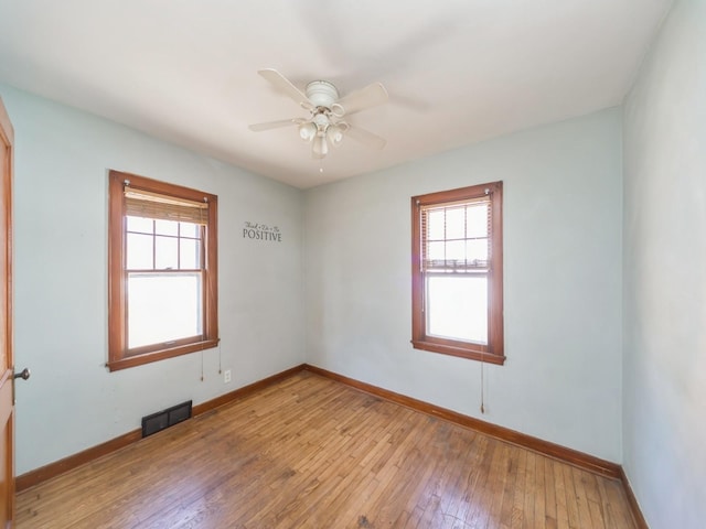 empty room with ceiling fan, baseboards, light wood-type flooring, and plenty of natural light