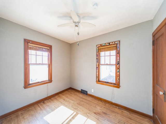 empty room featuring light wood finished floors, visible vents, and plenty of natural light