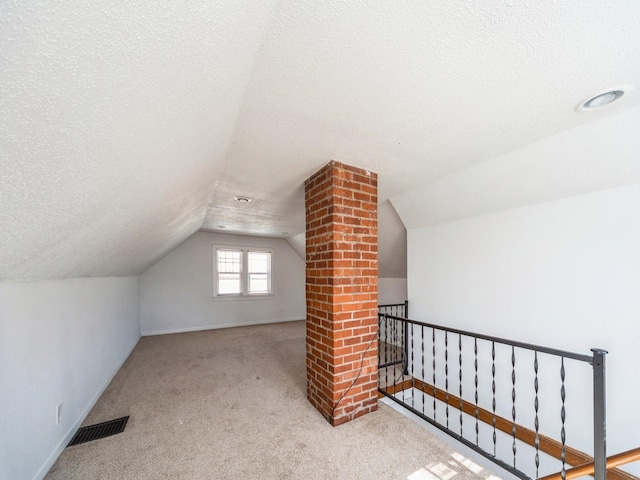 bonus room with carpet flooring, visible vents, a textured ceiling, and vaulted ceiling