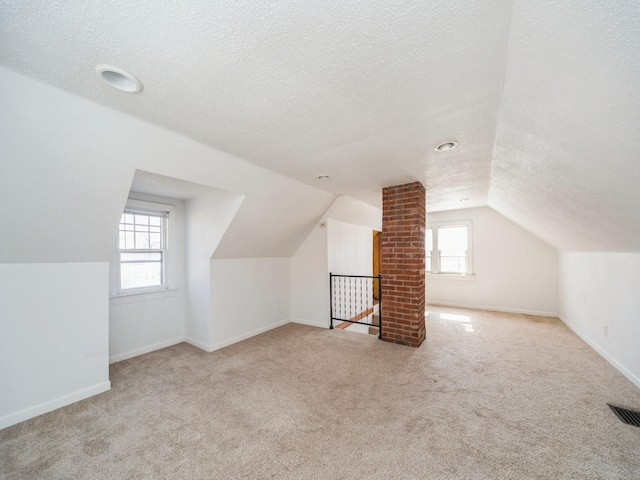 bonus room with lofted ceiling, a textured ceiling, visible vents, carpet flooring, and baseboards