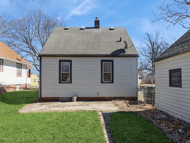 back of property with a patio area, a shingled roof, a chimney, and a lawn