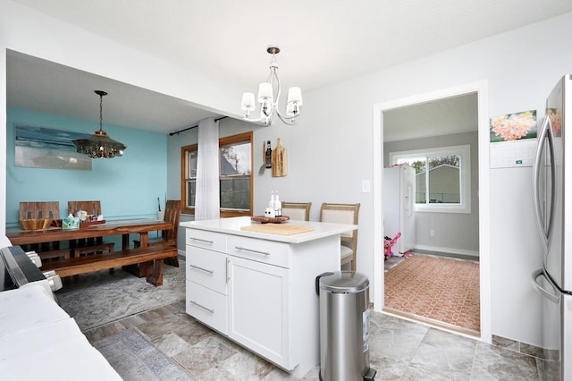 kitchen featuring an inviting chandelier, white fridge with ice dispenser, freestanding refrigerator, white cabinets, and light countertops
