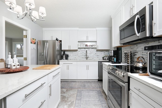 kitchen featuring tasteful backsplash, appliances with stainless steel finishes, a sink, and white cabinets