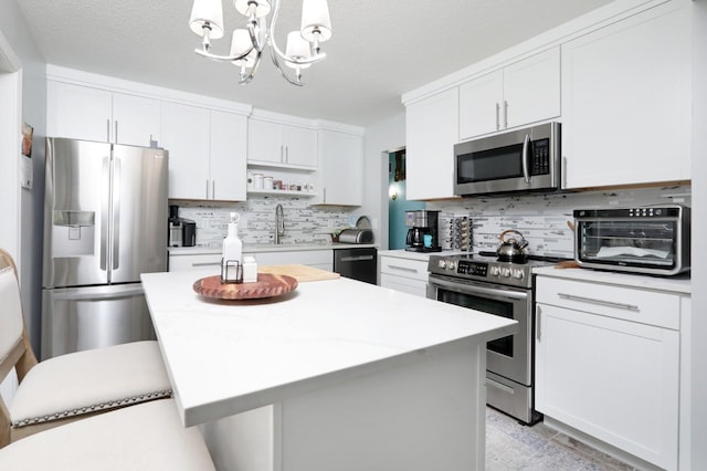 kitchen with stainless steel appliances, a sink, a chandelier, decorative backsplash, and light countertops
