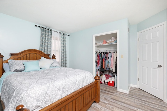 bedroom featuring a closet, visible vents, baseboards, light wood-style floors, and a spacious closet