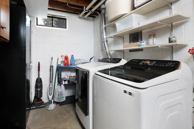 washroom featuring washer and dryer, laundry area, and concrete block wall