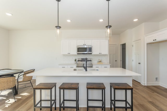935 11th St, Waukee, IA 50263 - kitchen with appliances with stainless steel finishes, light wood-style floors, white cabinetry, backsplash, and recessed lighting