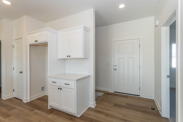 935 11th St, Waukee, IA 50263 - kitchen featuring wood finished floors, white cabinetry, light countertops, decorative backsplash, and recessed lighting
