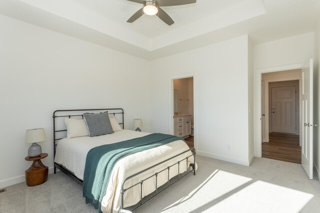 935 11th St, Waukee, IA 50263 - bedroom featuring light carpet, a tray ceiling, ensuite bathroom, and ceiling fan