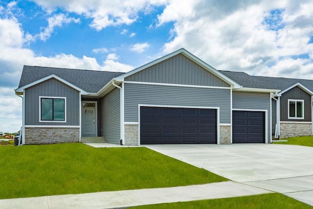 935 11th St, Waukee, IA 50263 - view of front of house with a garage, stone siding, driveway, a front yard, and roof with shingles