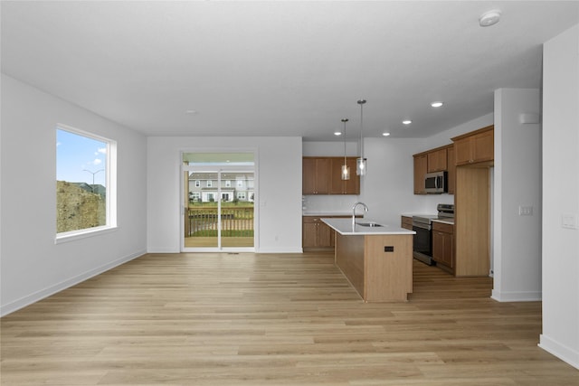 955 11th St, Waukee, IA 50263 - kitchen featuring stainless steel appliances, brown cabinetry, a sink, light countertops, and light wood finished floors