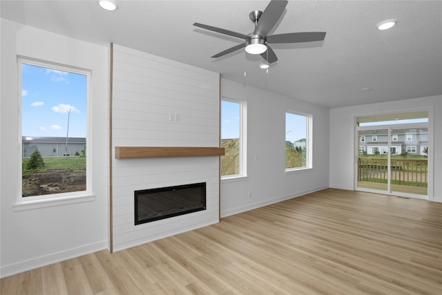955 11th St, Waukee, IA 50263 - unfurnished living room featuring a large fireplace, light wood-style flooring, ceiling fan, and recessed lighting