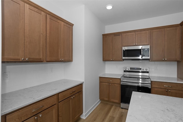 955 11th St, Waukee, IA 50263 - kitchen with stainless steel appliances, light wood-style flooring, tasteful backsplash, and brown cabinets