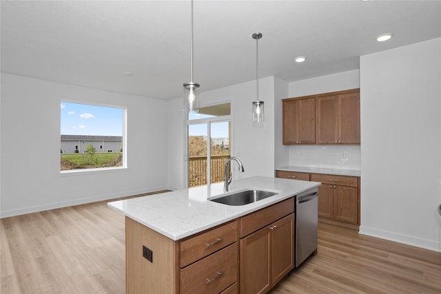 955 11th St, Waukee, IA 50263 - kitchen featuring a sink, stainless steel dishwasher, light wood-style flooring, decorative light fixtures, and a kitchen island with sink