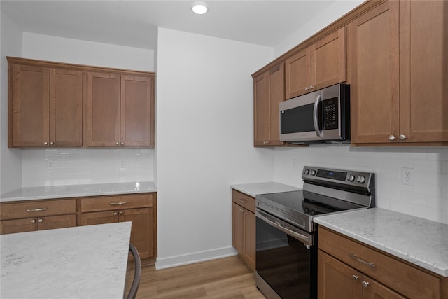 955 11th St, Waukee, IA 50263 - kitchen with appliances with stainless steel finishes, light wood-style flooring, brown cabinetry, tasteful backsplash, and recessed lighting