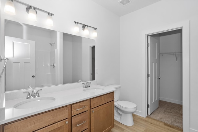 955 11th St, Waukee, IA 50263 - full bath with toilet, double vanity, wood finished floors, a shower, and a spacious closet