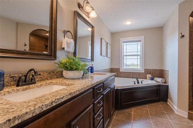 full bath with tile patterned floors, a garden tub, a sink, and double vanity