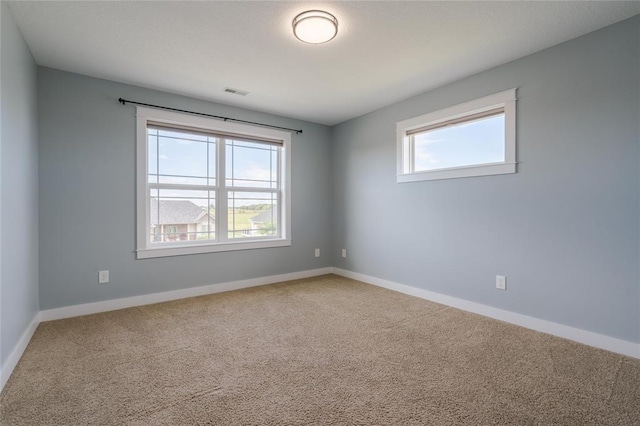 carpeted spare room featuring baseboards and visible vents
