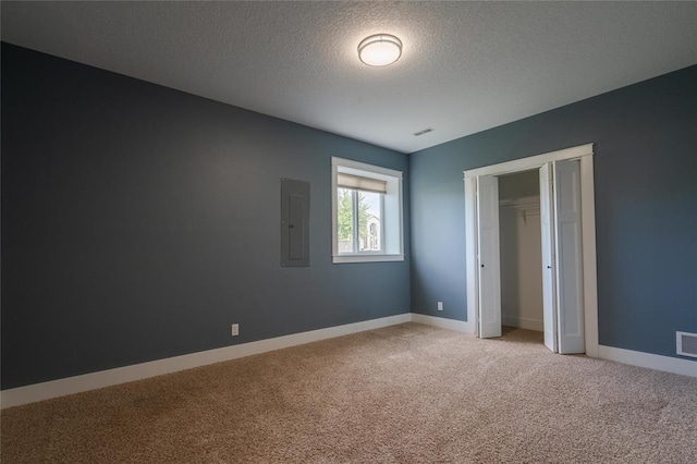 unfurnished bedroom featuring a textured ceiling, baseboards, visible vents, electric panel, and light carpet
