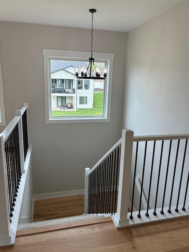 staircase with baseboards, a chandelier, and wood finished floors