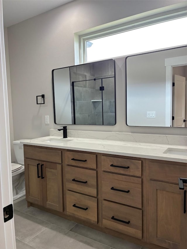 bathroom featuring a sink, toilet, tile patterned flooring, double vanity, and a tile shower