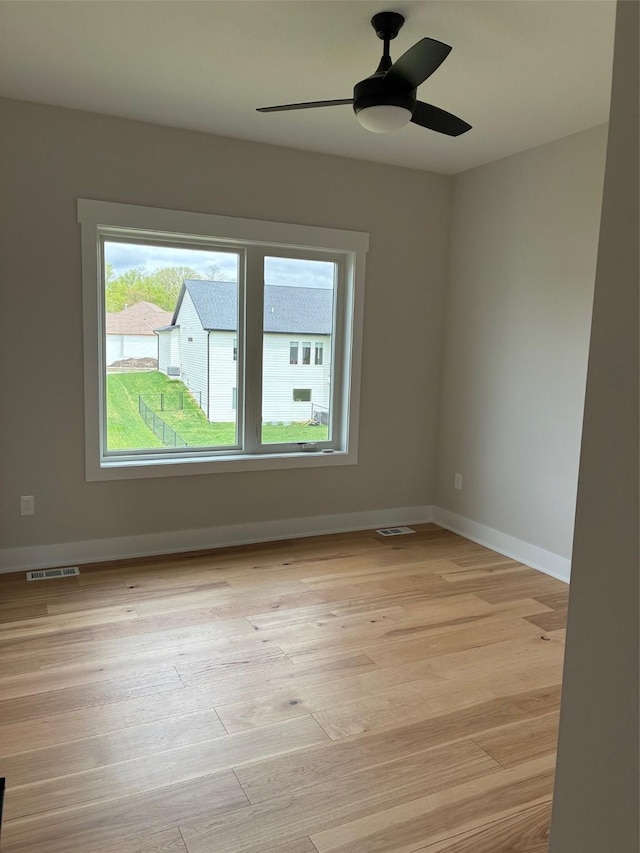 spare room with ceiling fan, baseboards, light wood-type flooring, and visible vents