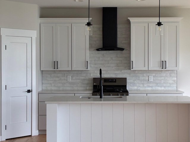 kitchen with a sink, wall chimney range hood, backsplash, and light countertops