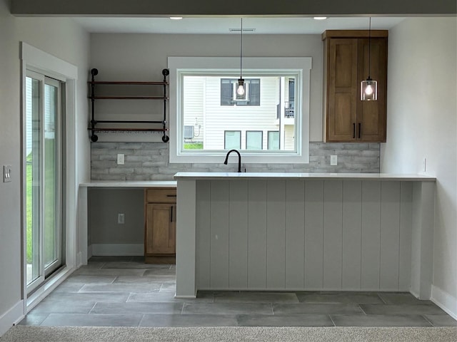 kitchen with wood tiled floor, backsplash, light countertops, and brown cabinets