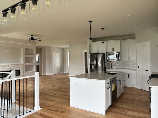 kitchen featuring recessed lighting, a sink, open floor plan, light wood-style floors, and stainless steel appliances