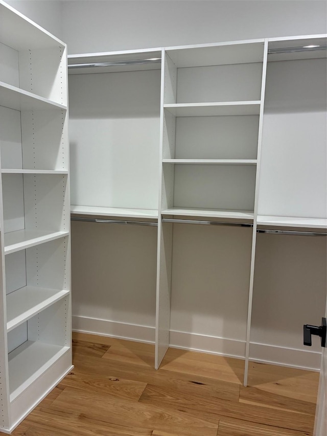 walk in closet with wood finished floors