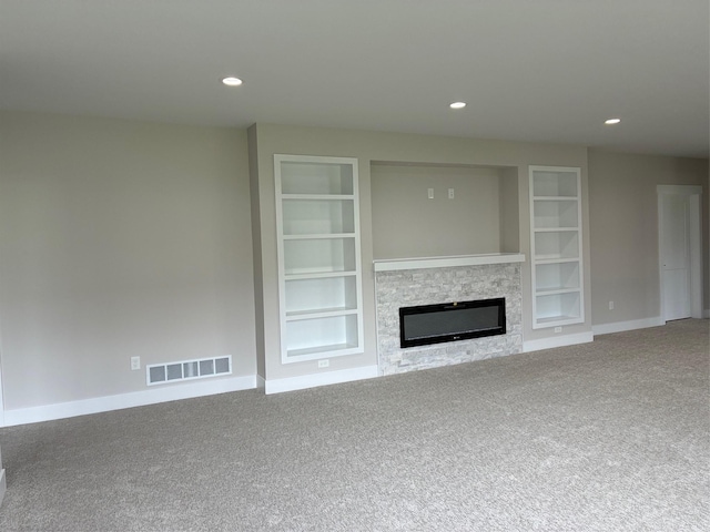 unfurnished living room with visible vents, built in features, a fireplace, carpet flooring, and baseboards
